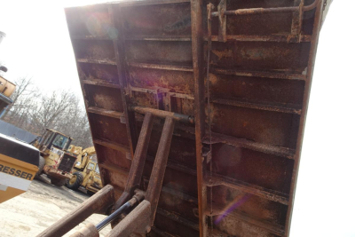 Dump truck bed and hydraulic lift of a Mitsubishi FH dump truck with rusted metal and hydraulic arms visible
