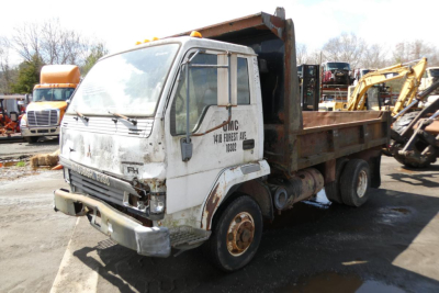 Dump truck cab and bed showing Mitsubishi FH model with white cab and rusted dump body, front view angled left.