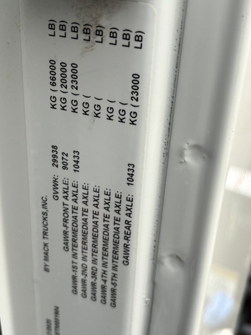 Label on Mack truck showing GVWR and axle weights: GAWR FRONT AXLE 6,000 KG? (not fully clear), GAW? REAR AXLE: 23,000 KG? plus various bearing weights and VIN tag text.