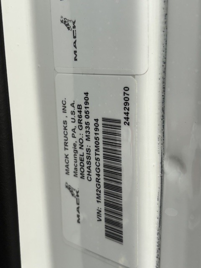 Mack GR64B chassis label and VIN sticker showing manufacturer and barcode. Text includes MAC TRU... MACK TRUCKS INC, MACK/P.A., USA, CHASSIS: M ... VIN: 1M2GR4GC5TM051904, stock number 24429070.