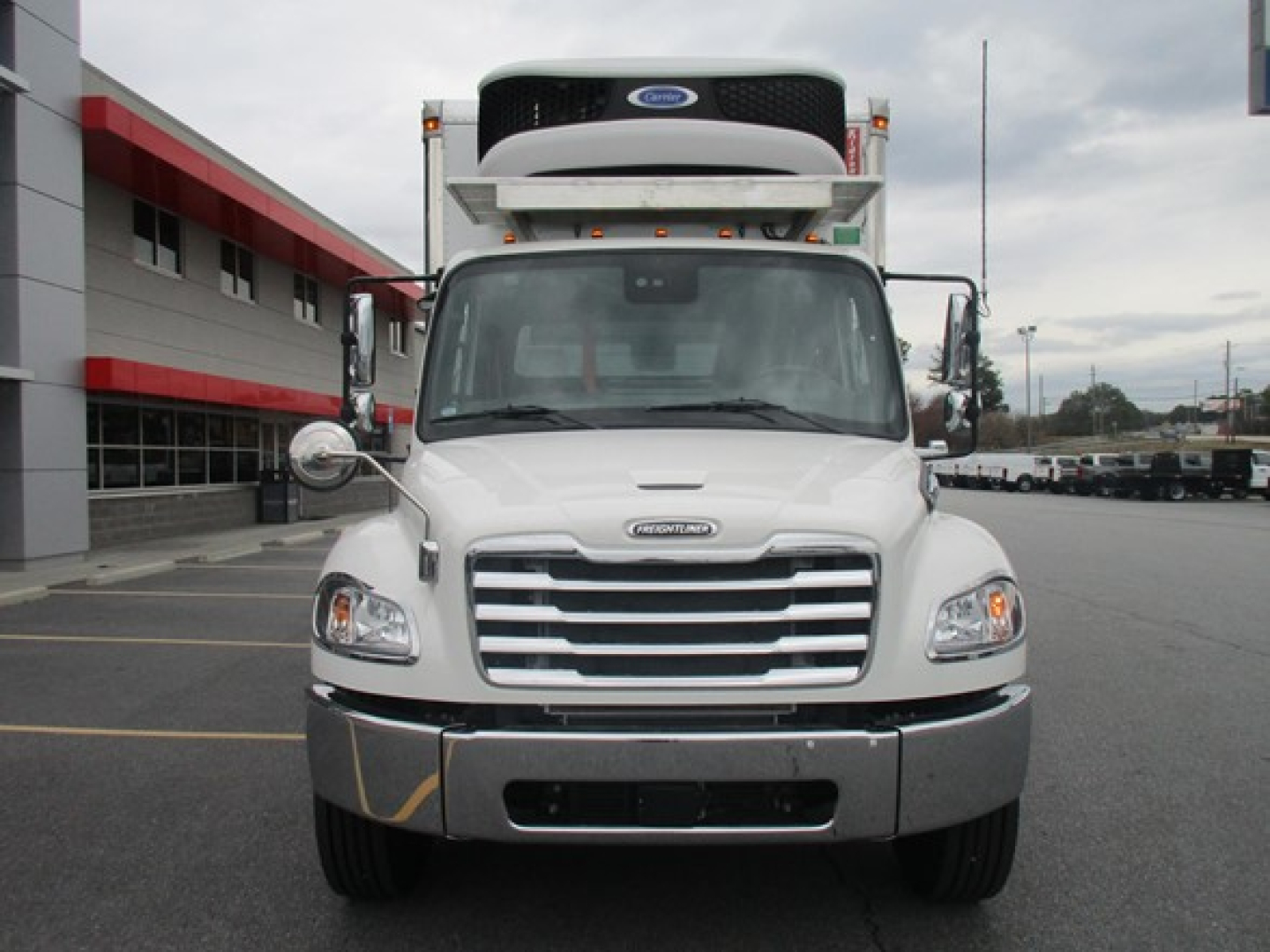 Freightliner M2 106 Plus front view with refrigerated body, white cab, and rooftop unit.