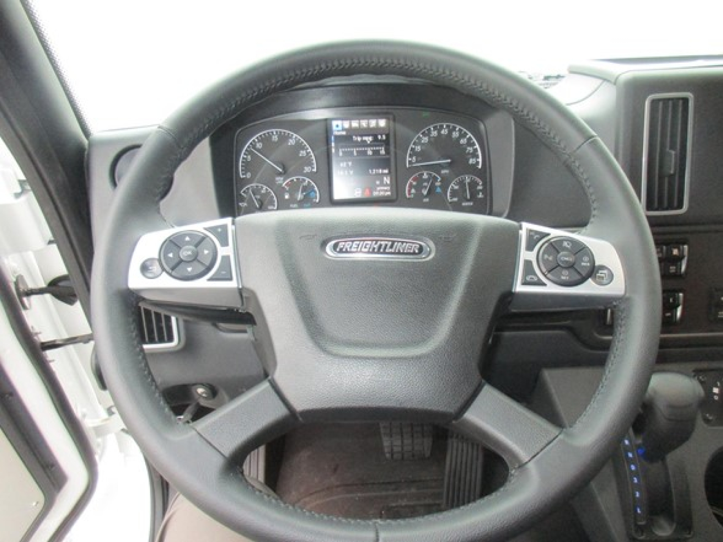 Steering wheel and instrument cluster of a Freightliner M2 106 Plus interior view showing steering wheel controls and dash gauges.