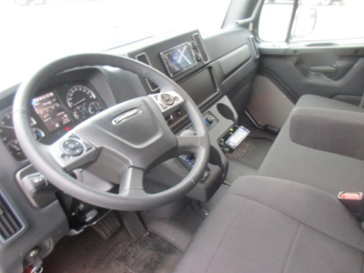 Freightliner M2 106 Plus interior showing steering wheel, dashboard, and center console with touchscreen display.