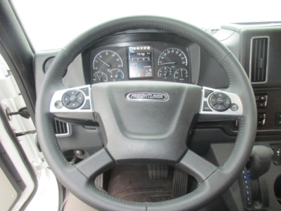 Steering wheel and instrument cluster of a Freightliner M2 106 Plus interior view showing steering wheel controls and dash gauges.