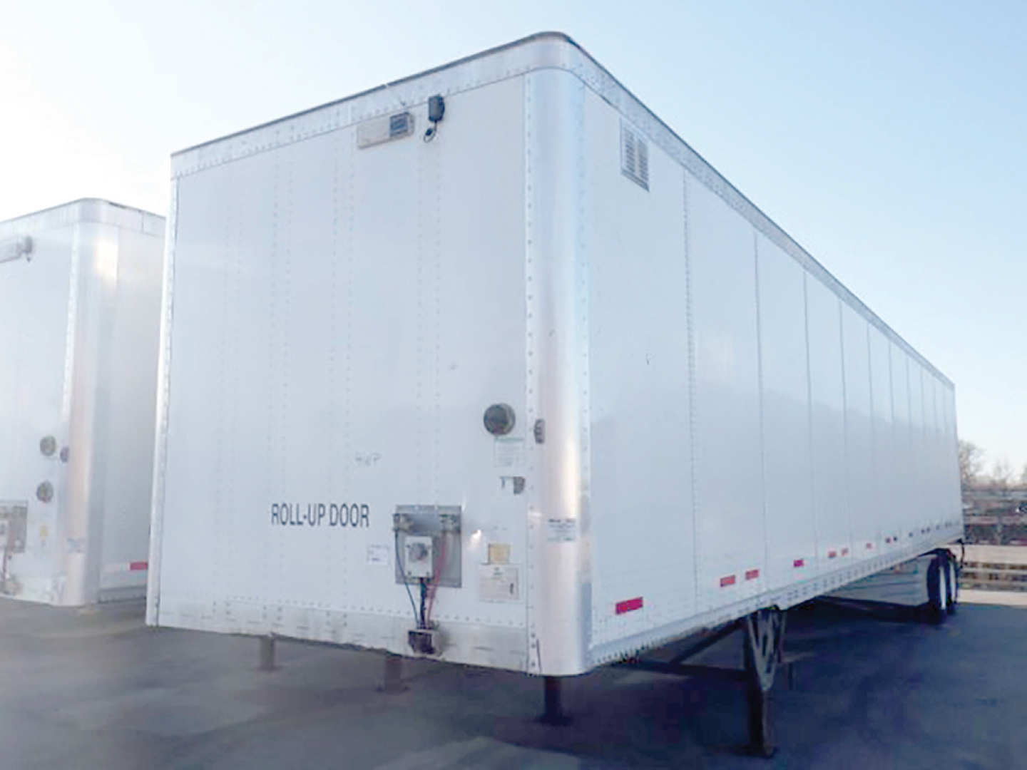 Wabash dry van trailer showing roll-up door and rear corner, white exterior.