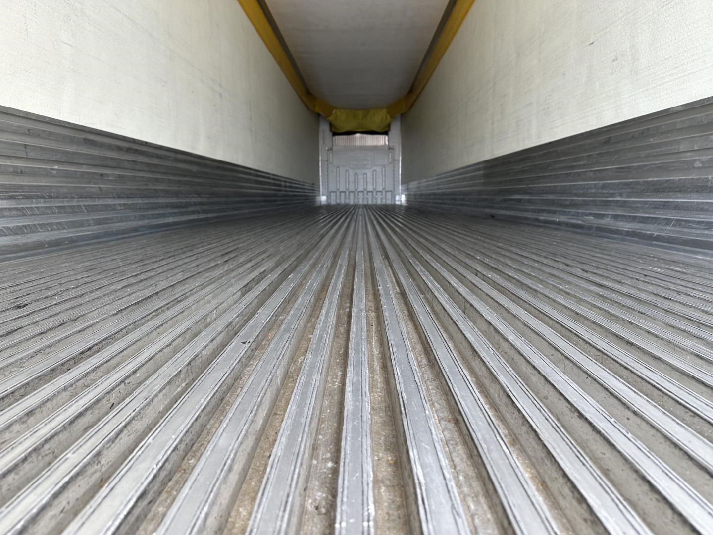 Trailer interior cargo area showing corrugated floor and rear door opening in a reefer trailer.