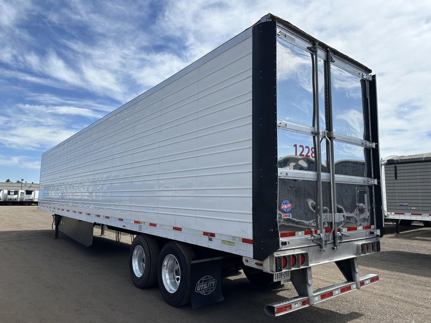 Utility 3000R trailer in side and rear view showing aluminum body, twin rear doors, bumper, and dual rear wheels.