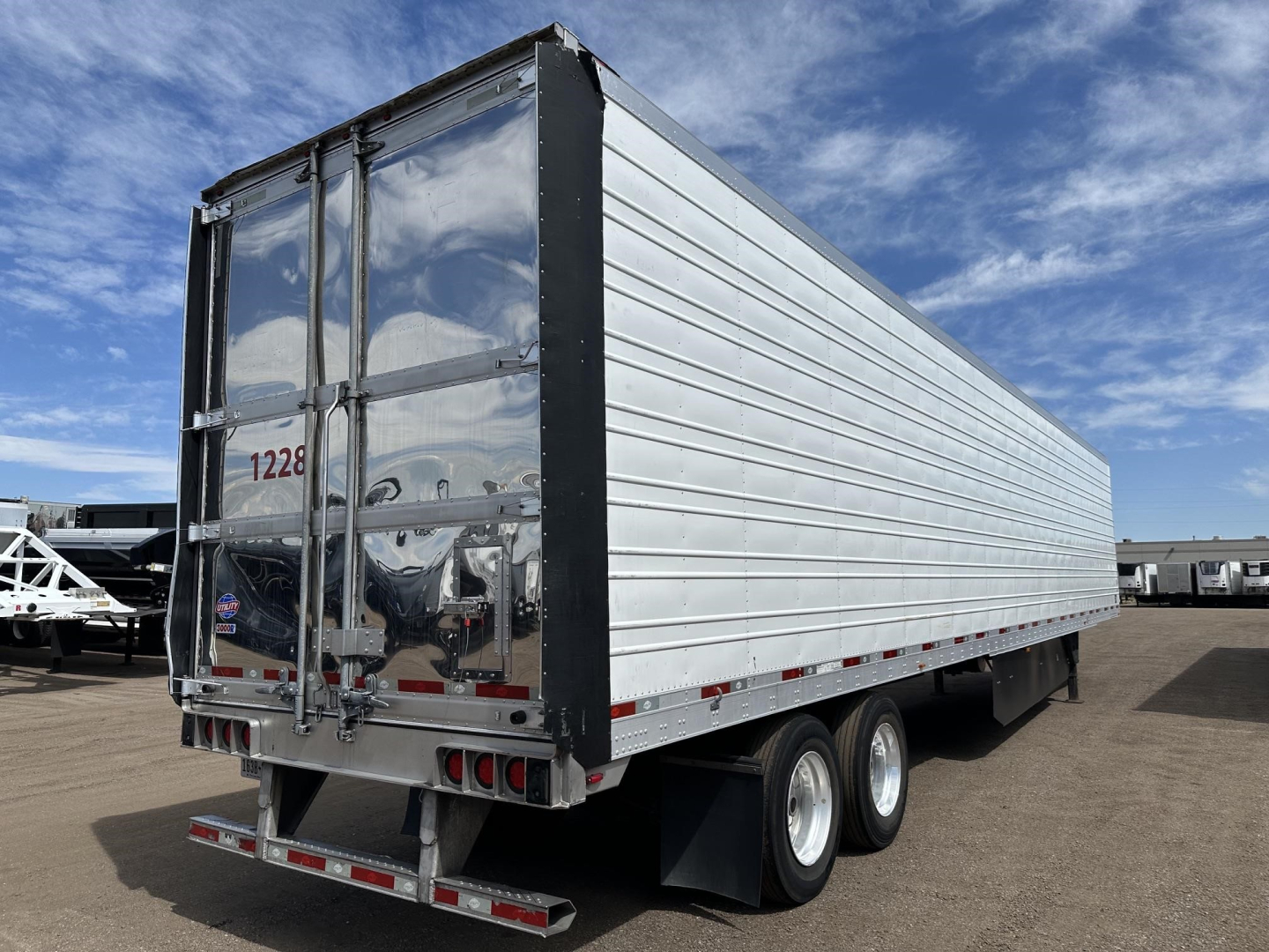 Trailer side and rear of a 2022 Utility 3000R refrigerated trailer, aluminum walls, dual rear doors, black frame, on a dealership lot.