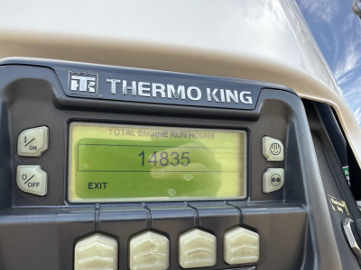 Thermo King unit on a trailer showing Total Engine Run Hours 14835 on a green backlit display; surrounding control buttons visible.