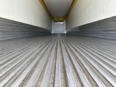 Trailer interior cargo area showing corrugated floor and rear door opening in a reefer trailer.