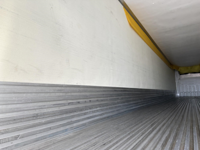 Trailer interior cargo area with ribbed metal floor and side wall, empty cargo space, rear door open showing aluminum threshold.