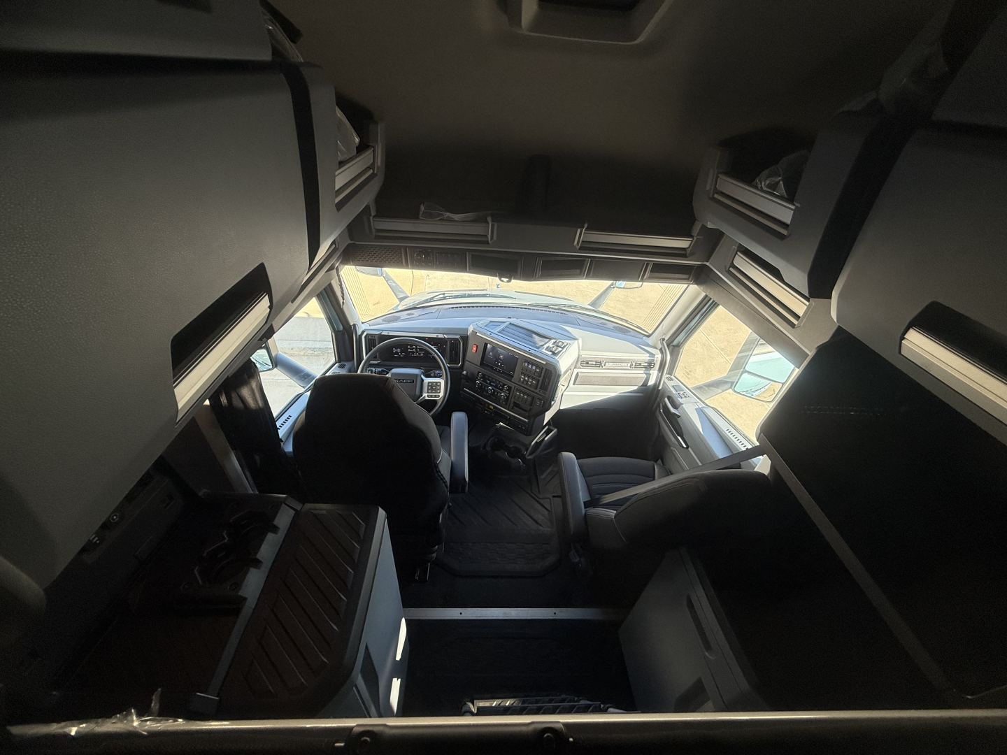 Cab interior of a Mack PR64T76H truck viewed from above, with dashboard, steering wheel, and bunk area visible.