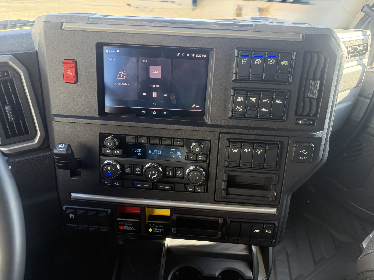 Dashboard of a 2026 Mack PR64T76H showing a center touchscreen, climate controls, switches, and instrument panel.