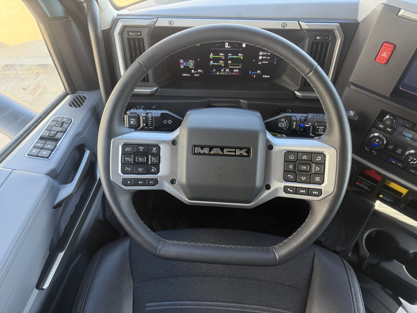 Mack truck steering wheel and dashboard inside cab showing control buttons and digital gauges