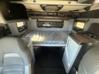 Mack PR64T76H truck cab interior showing sleeping area with overhead controls, compact dinette, and storage cabinets.