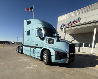 2026 Mack PR64T76H truck in light blue exterior parked outside dealership showing front grille with MACK emblem and sleeper cab.
