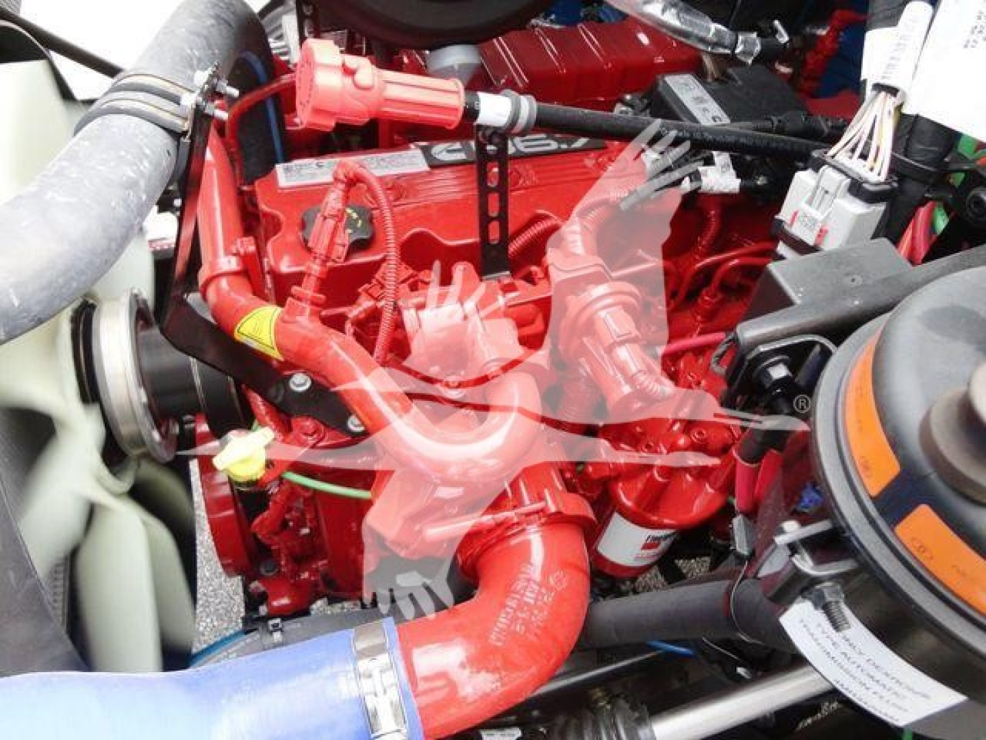 Engine bay of a 2027 Mack MD6 rollback truck showing bright red engine components and hoses.