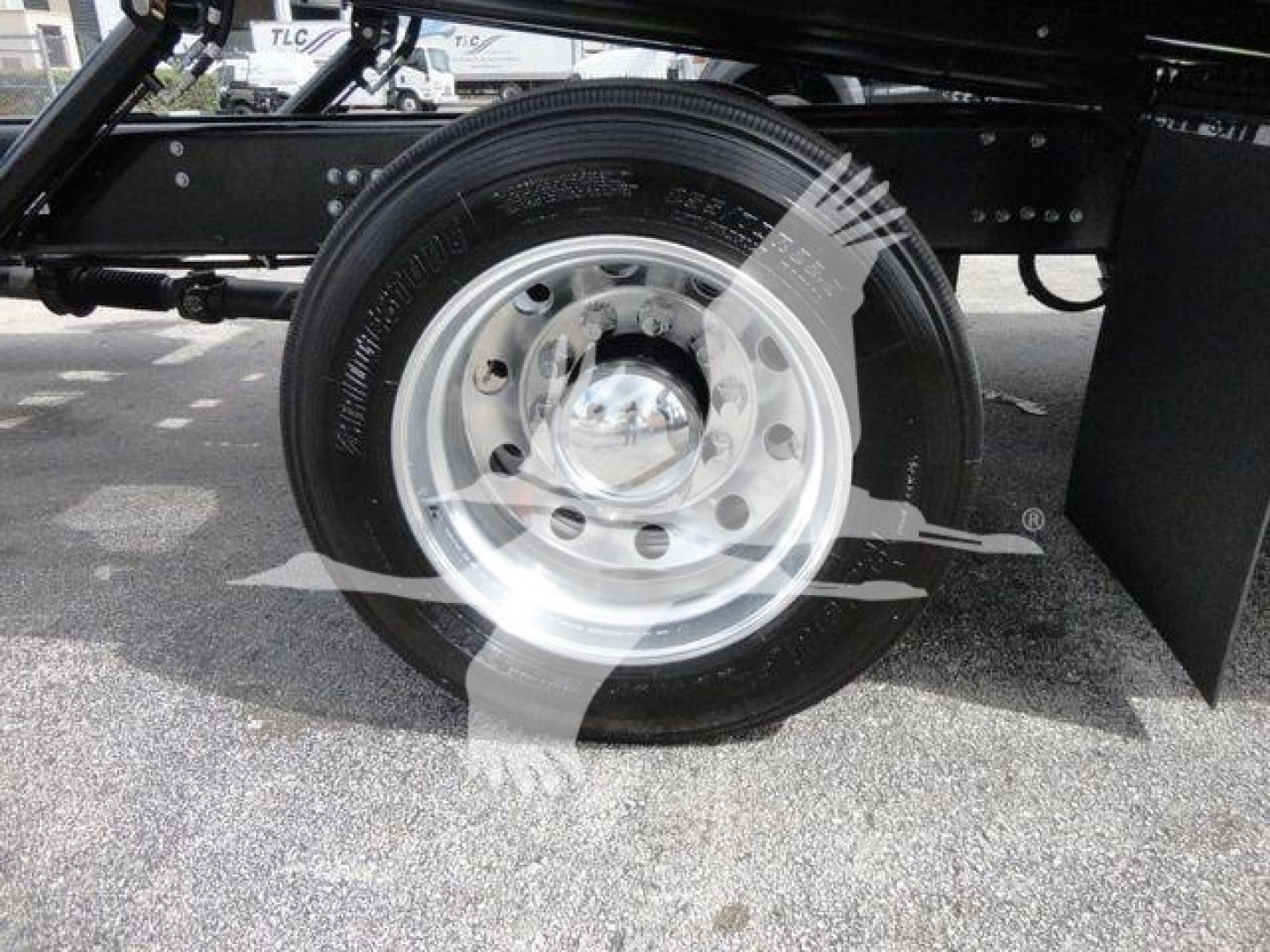 Rear wheel and suspension of a 2027 Mack MD6 rollback truck on a paved lot.