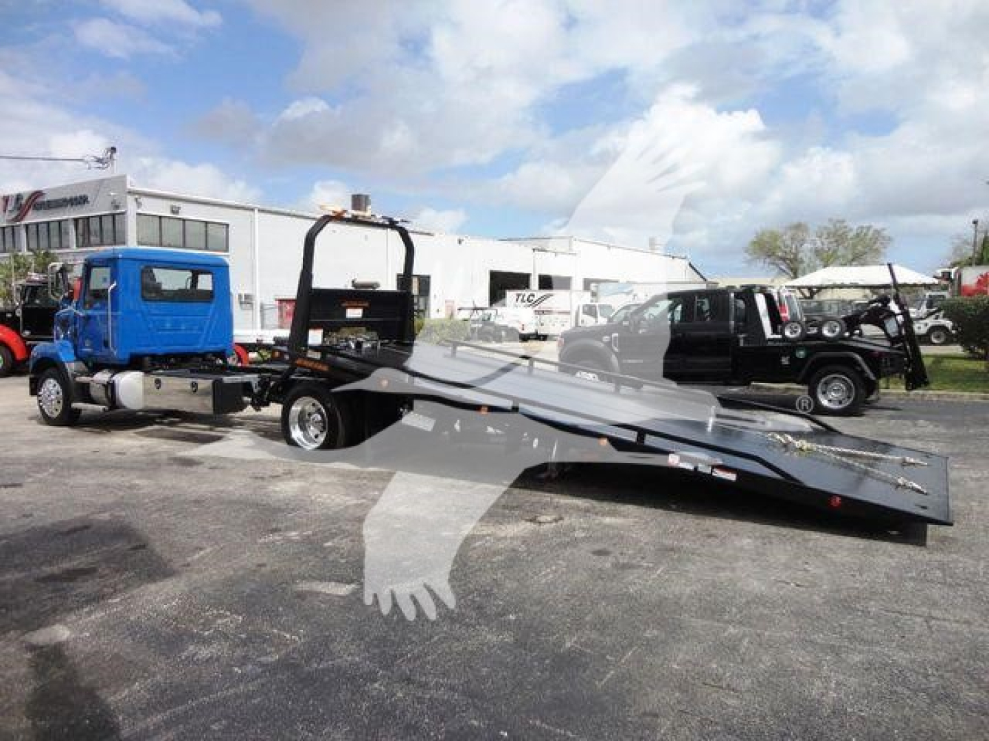 New 2027 Mack MD6 rollback truck with a lowered flatbed in a dealership lot.