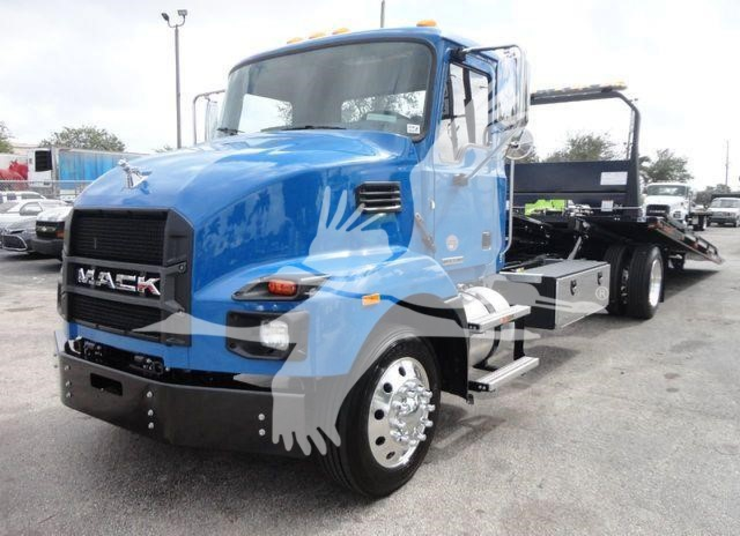 2027 Mack MD6 rollback truck front-left view with bright blue cab and black bumper, chrome wheels, and flatbed trailer behind.