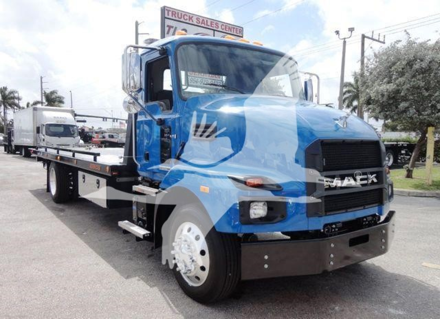 Mack MD6 rollback truck showing front view and blue cab with flatbed in service bay.