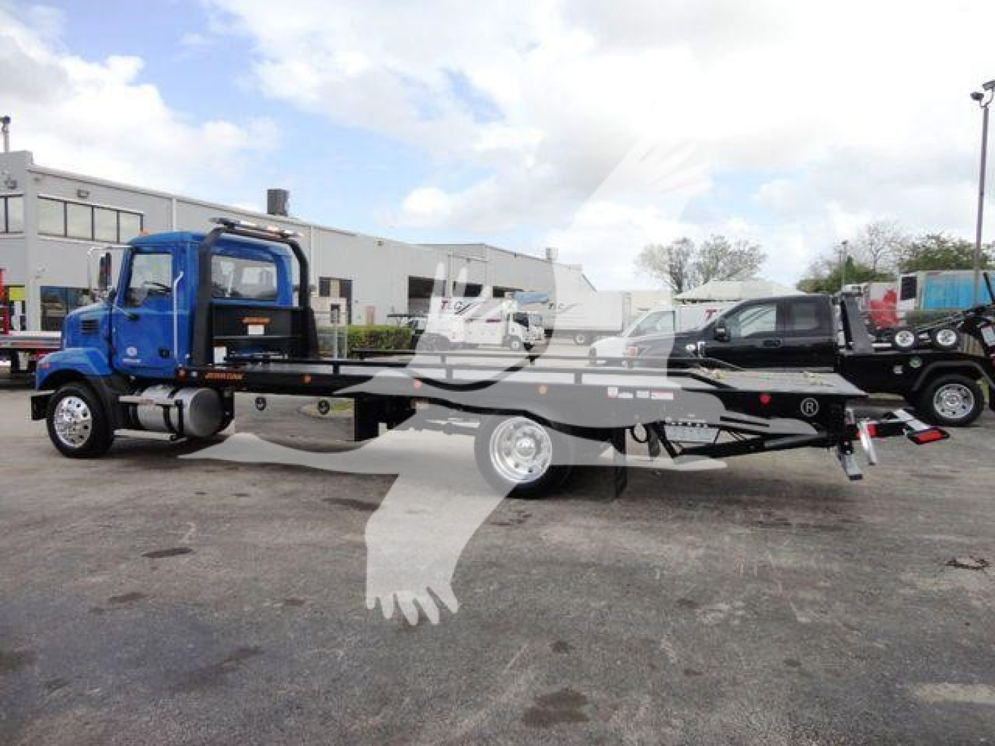 Mack MD6 rollback truck showing blue cab and flatbed carrier with model details not visible.