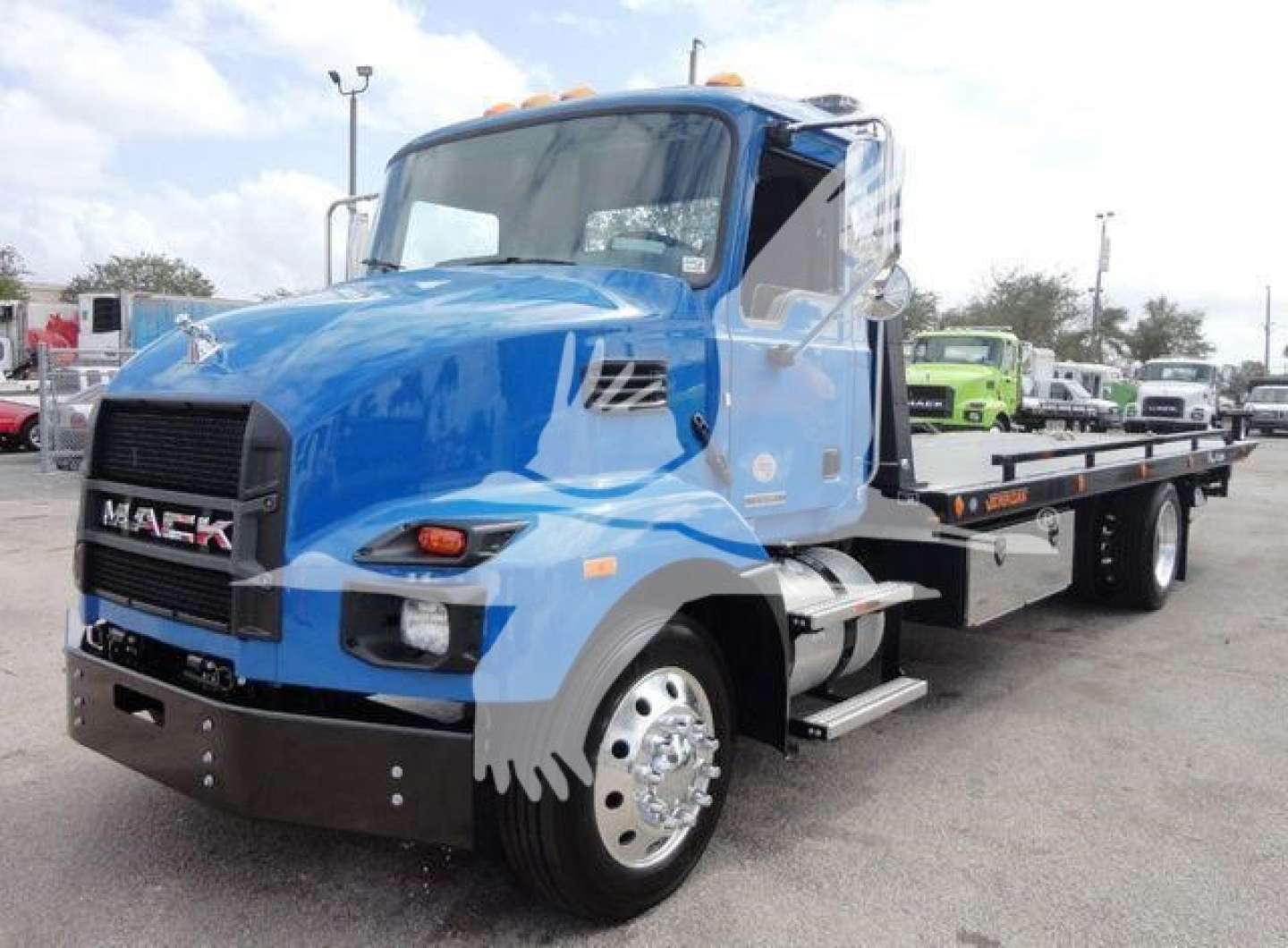 Mack MD6 tow truck in blue with black front bumper and flatbed, side view showing cab and dual rear wheels.