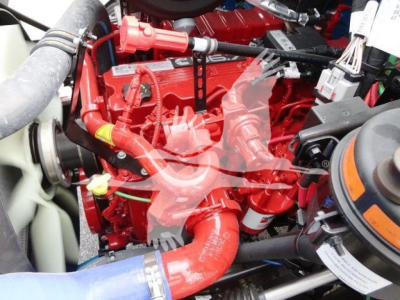 Engine bay of a 2027 Mack MD6 rollback truck showing bright red engine components and hoses.
