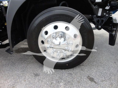Truck front wheel and hub showing steel wheel with multiple circular holes and black tire under Mack MD6 rollback truck.