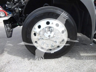 Front wheel and tire on a Mack MD6 truck showing polished aluminum hub and black tire with tread.