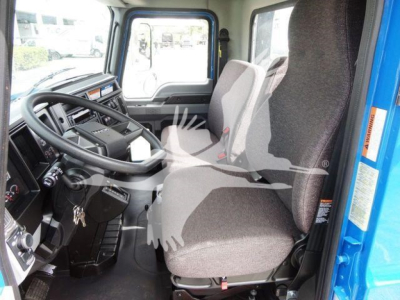 Interior driver seat and dashboard of a Mack MD6 truck cabin with steering wheel, gear shifter, and two front seats visible.