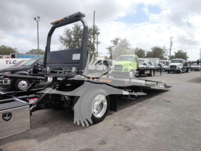 Mack MD6 rollback truck chassis showing platform and rear wheels with hydraulic system components visible.