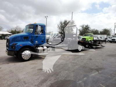 Blue Mack MD6 truck in a rollout yard with a flatbed trailer and other trucks in background, stock number J04369.