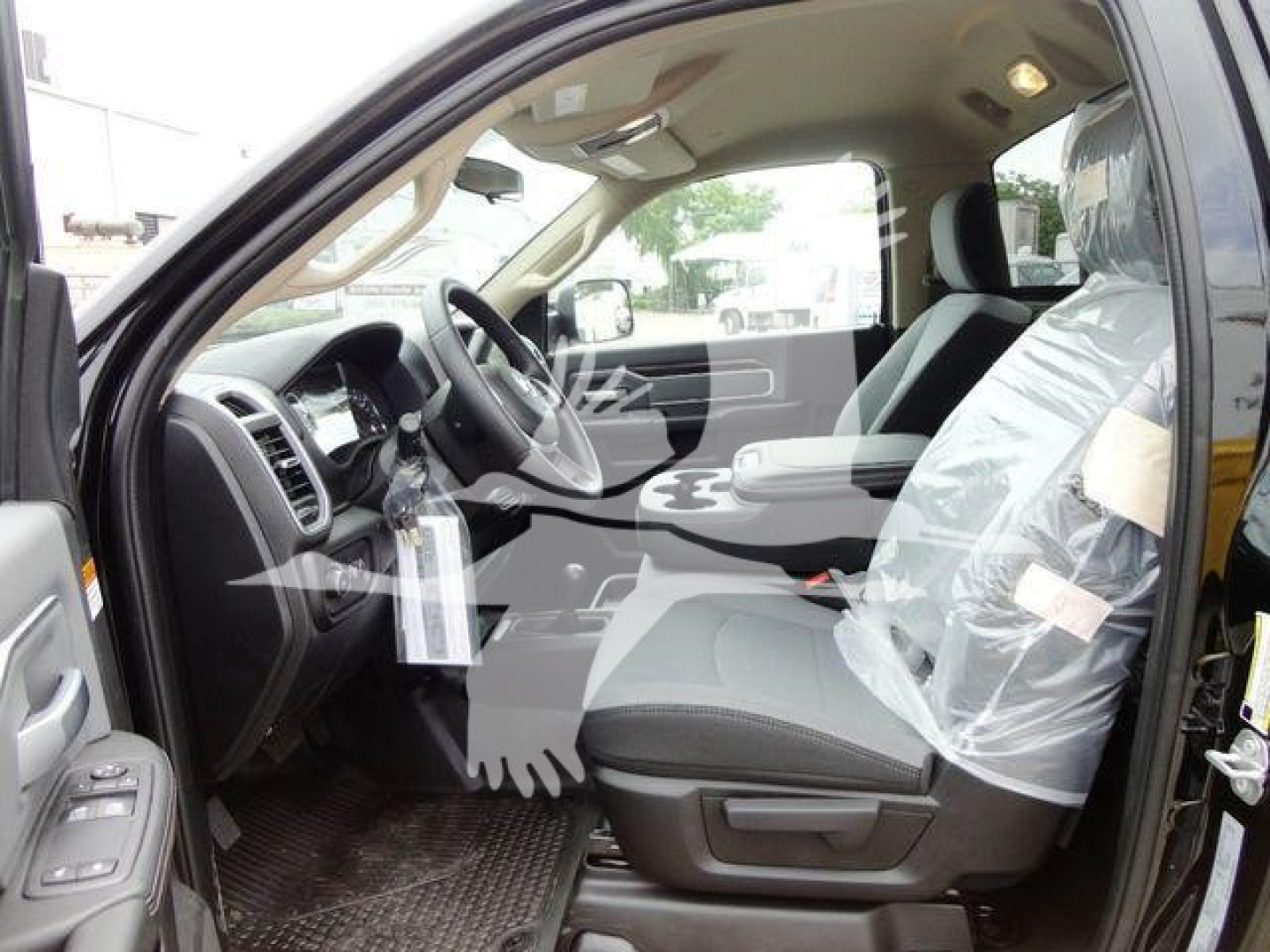 Cab interior of a 2024 Ram 4500 SLT pickup with plastic-covered seats and steering wheel visible from the driver’s door.