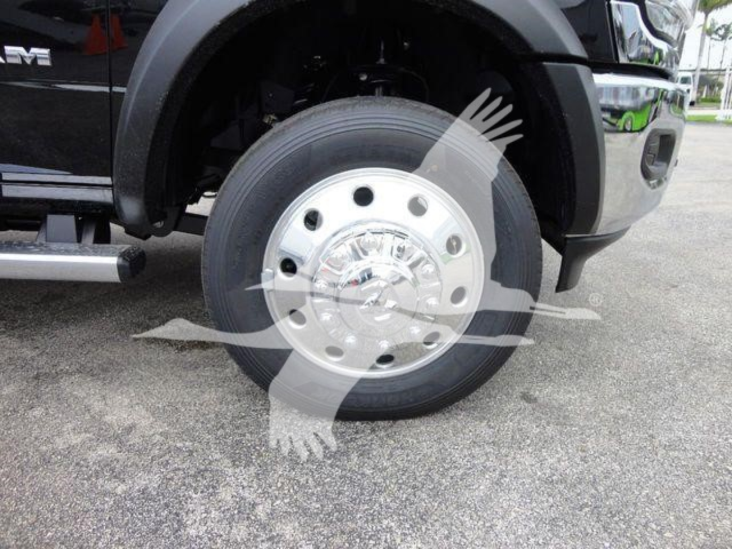 Front wheel of a 2024 Ram 4500 SLT showing polished aluminum hub with multiple lug nuts and tire, partial black fender and side steps visible.