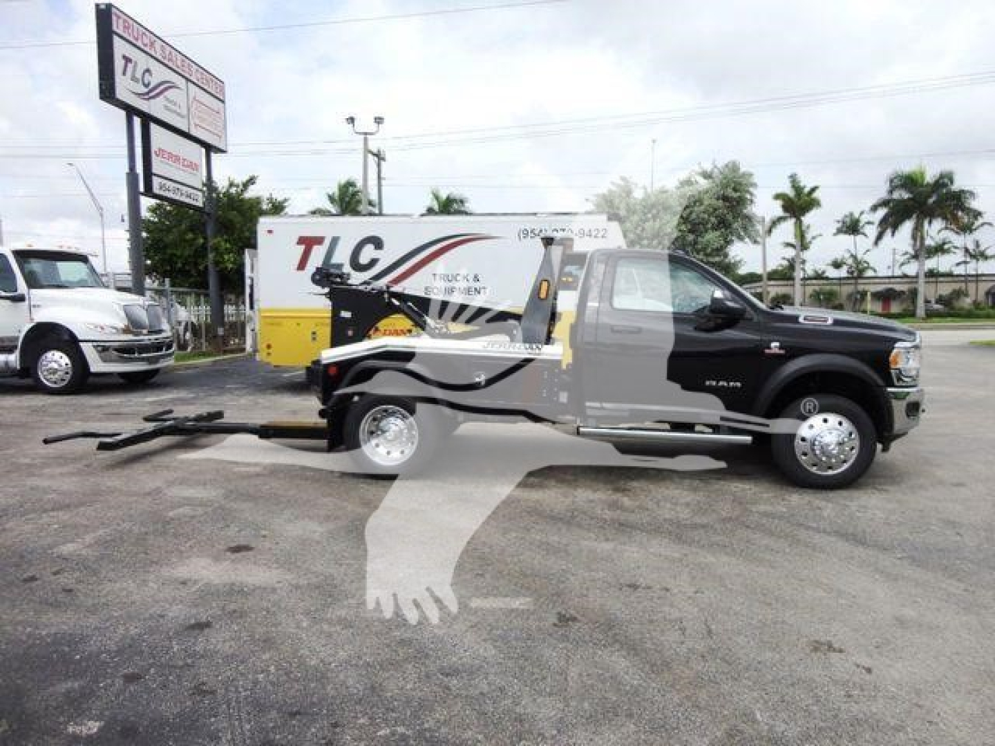 Ram 4500 SLT pickup truck with winch equipment in bed, side view showcasing tow setup and TLC sign in background.