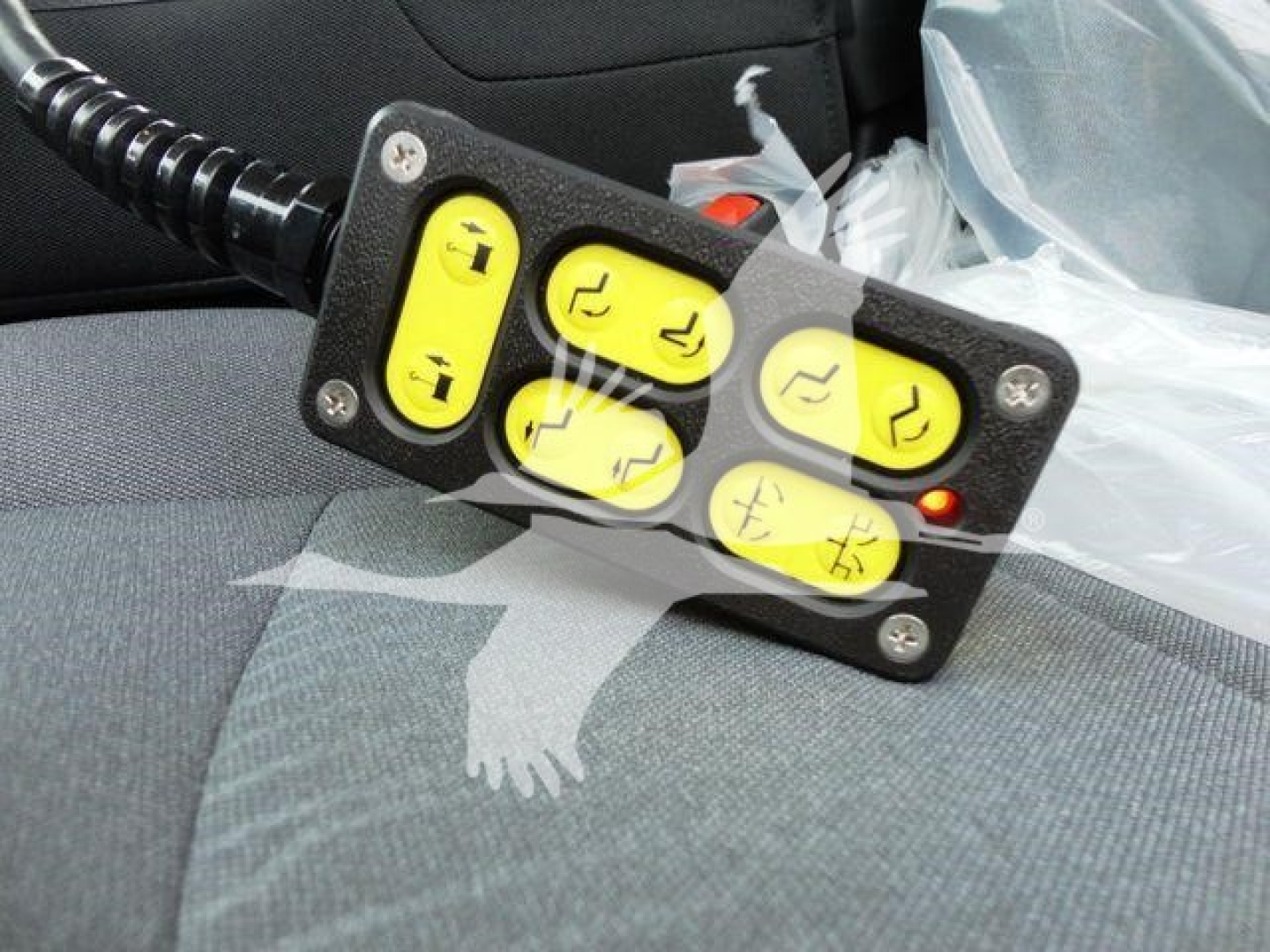 Winch remote control unit with yellow buttons on fabric interior of a truck seat.