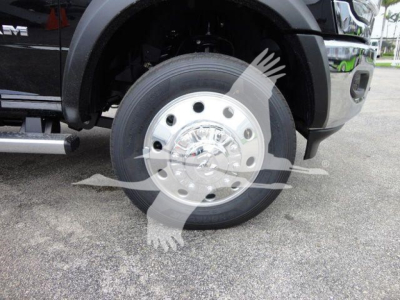 Front wheel of a 2024 Ram 4500 SLT showing polished aluminum hub with multiple lug nuts and tire, partial black fender and side steps visible.