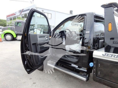 Truck interior with open front door showing Ram 4500 SLT cab and steps, dashboard, and steering wheel; part of winch-equipped truck visible in background