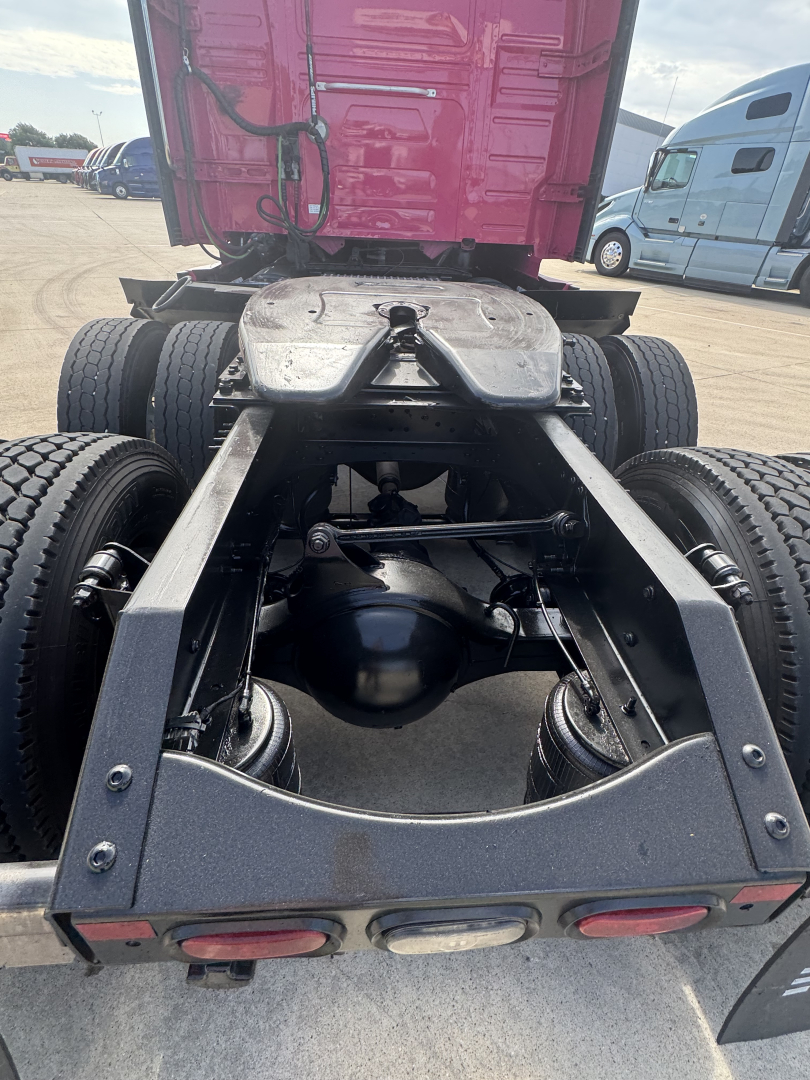 Truck chassis rear view showing fifth wheel, suspension, drive axles, and rear fenders with dual rear wheels.