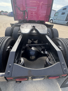 Truck chassis rear view showing fifth wheel, suspension, drive axles, and rear fenders with dual rear wheels.