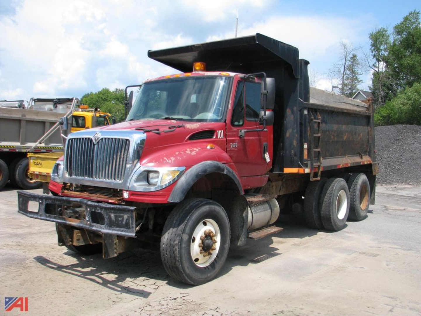 Dump truck showin g 2005 International 7600 WorkStar with red cab and black dump body in a yard.