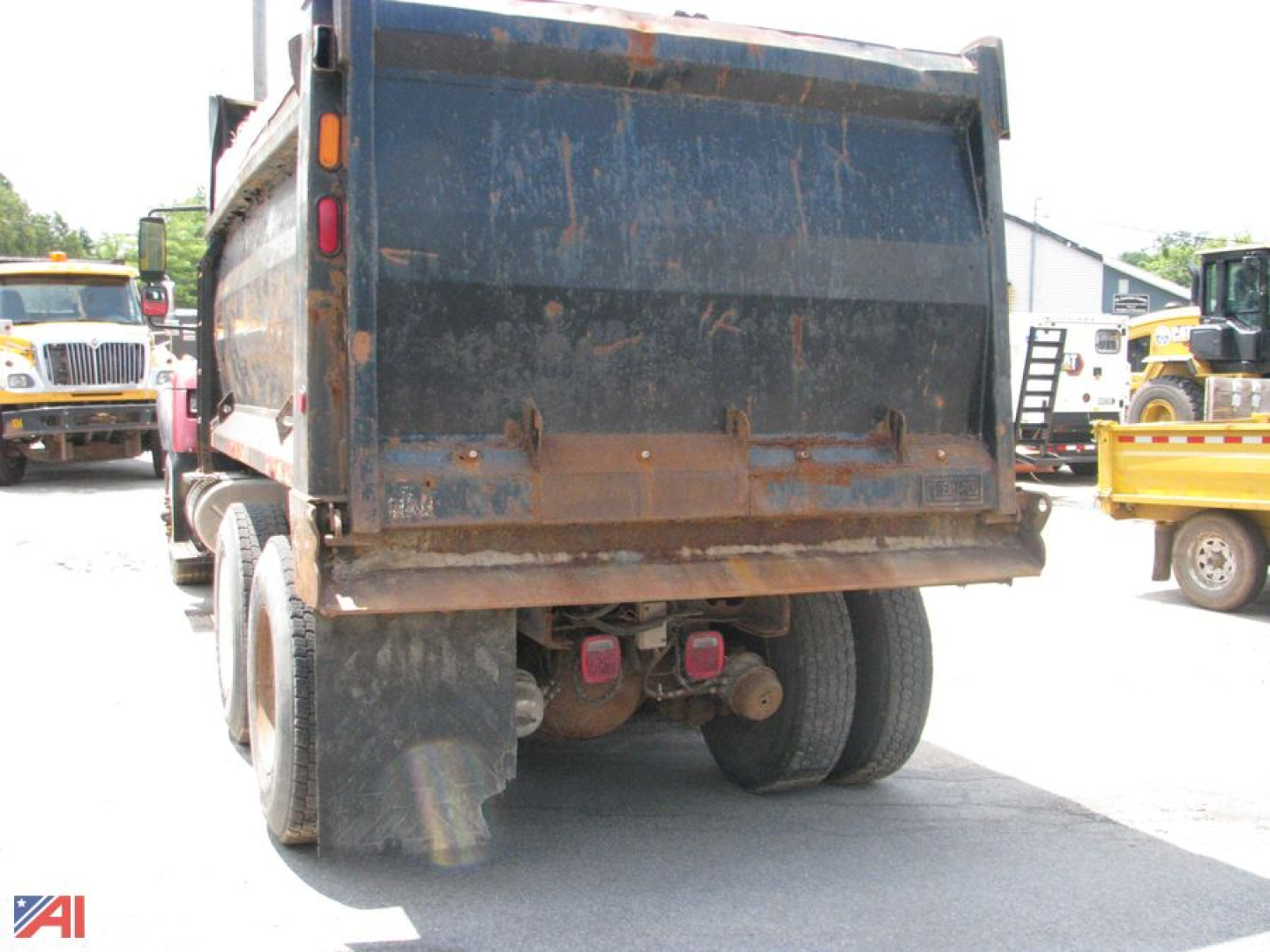 Dump truck rear view showing International 7600 WorkStar equipment with large blue dump box and dual rear wheels.