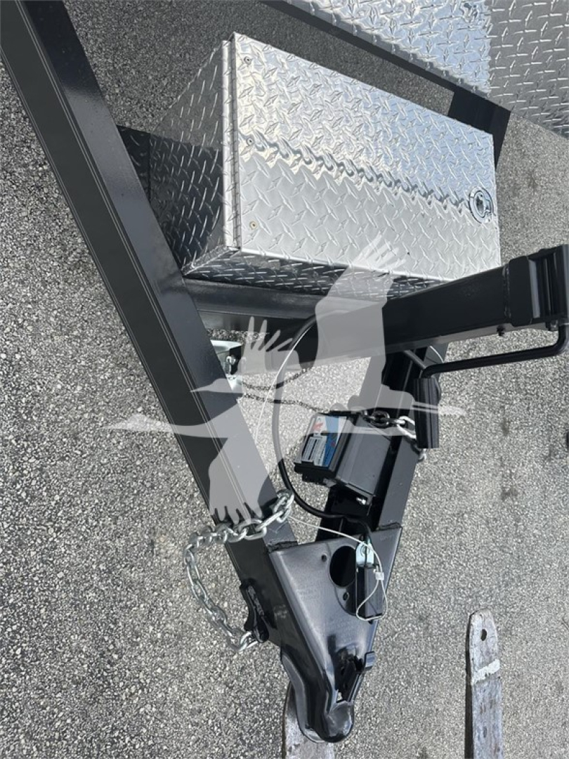 Trailer hitch tongue and diamond plate toolbox on a trailer frame with trailer jack and safety chains visible.