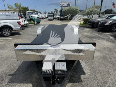 Rear view of a 24 ft trailer with a diamond plate toolbox mounted at the front, and a hitch assembly visible, in a dealership lot.