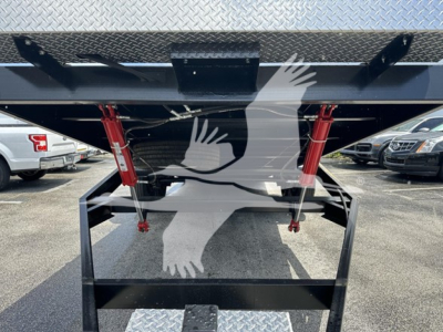 Trailer underside with red hydraulic support legs and diamond plate rear deck showing mechanical frame and support beams.