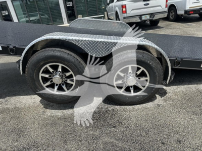 Trailer deck with dual wheels and diamond plate fenders; visible text on vehicle components reads nothing legible; overall shows wheel wells and part of the steel trailer frame.