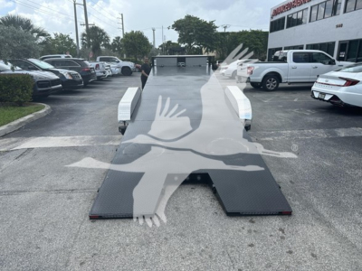 Trailer with flatbed ramp in a parking lot, platform unfolded, metal diamond plate surface, white side rails.