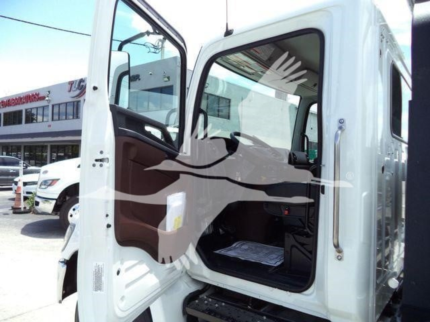 Truck cab interior and open door of a 2026 Hino L6 rollback truck showing cabin doorway and partial dashboard area.
