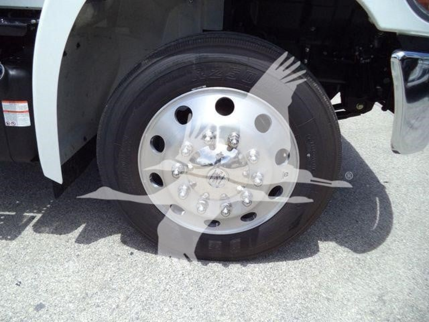 Truck wheel with polished steel hubcap and tire, front wheel well visible and fender in view.